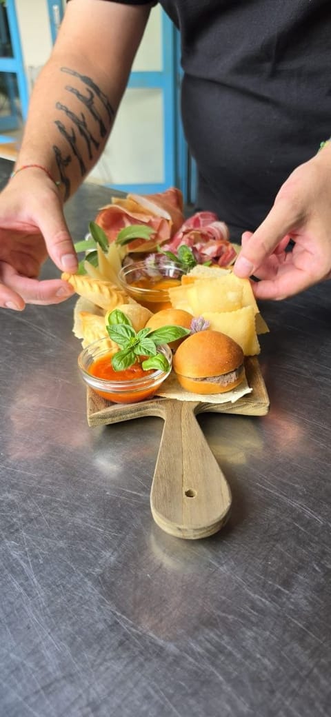 Tagliere aperitivo con mini burger, prosciutto crudo, ravioli fritti e salse, servito a mano