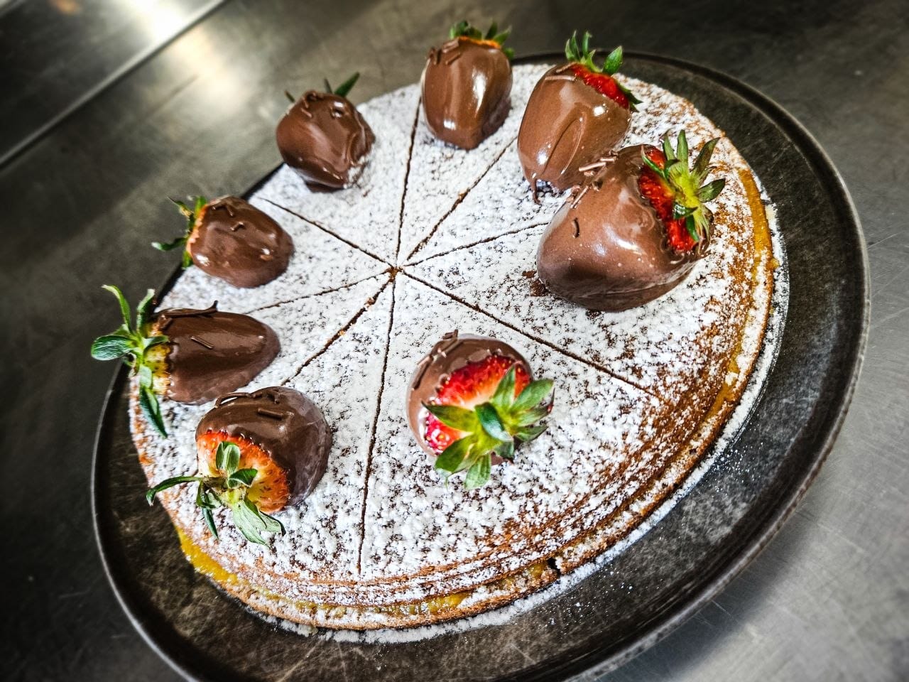 Crostata al cioccolato con zucchero a velo e fragole ricoperte di cioccolato fondente