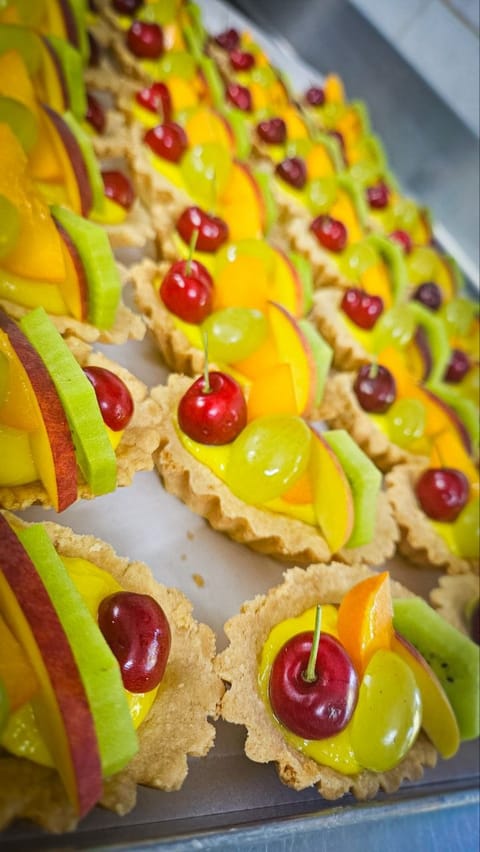 Crostatine monoporzione con crema e frutta fresca in fila sul vassoio
