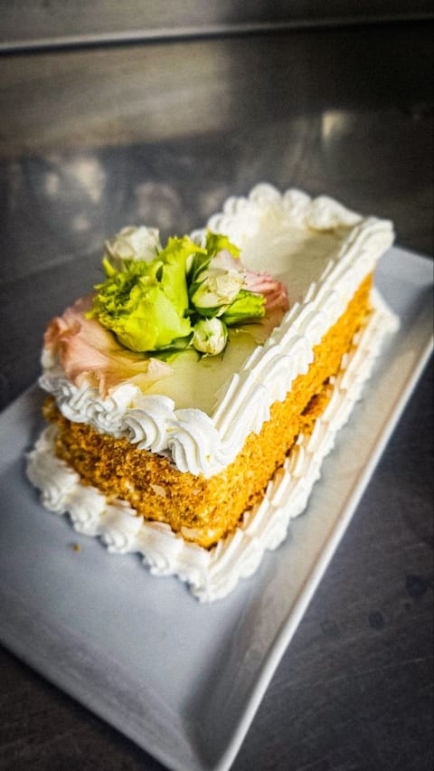 Fetta di torta alle mandorle rifinita a sac à poche e guarnita con fiori edibili