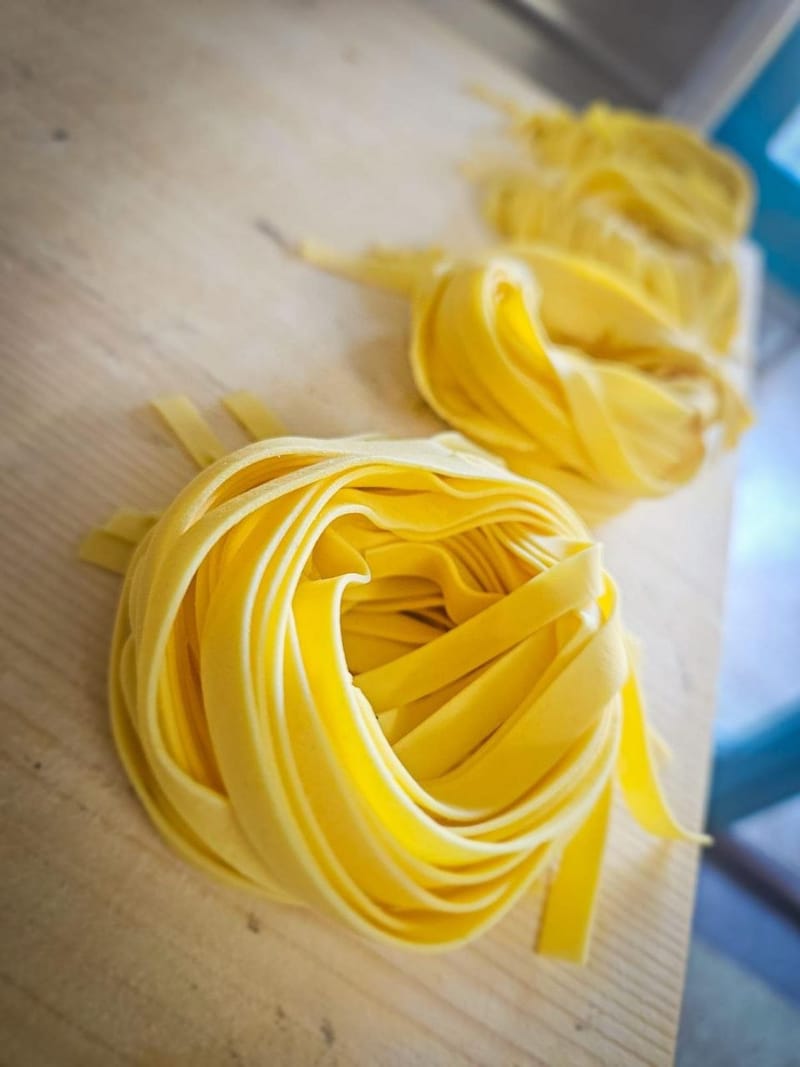 Nidi di tagliatelle fresche all'uovo su tagliere di legno
