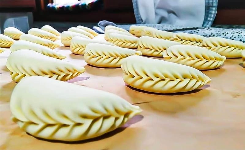 Culurgiones crudi chiusi a spiga uno per uno, in fila sul piano di lavoro
